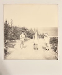 three people standing on a dirt road