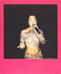 a woman is holding a microphone in front of a pink polaroid