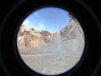 a view of a waterfall through a hole in the ground