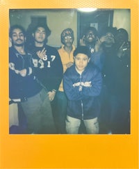 a group of people posing in front of a yellow polaroid