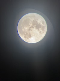 a full moon is seen in the dark sky