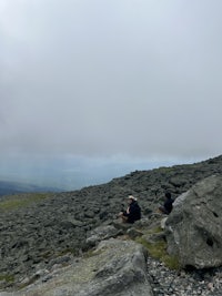 two people standing on top of a rocky cliff